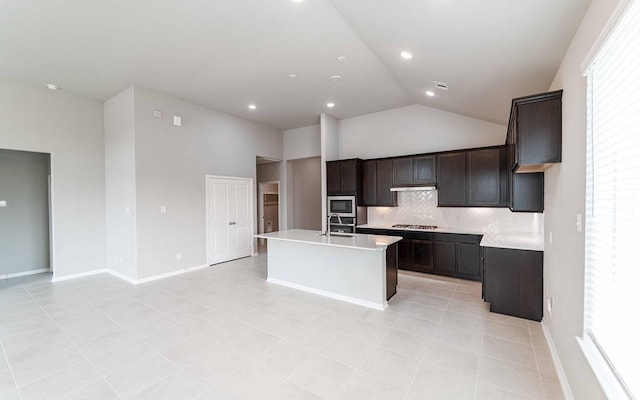 kitchen featuring sink, high vaulted ceiling, a center island with sink, appliances with stainless steel finishes, and backsplash