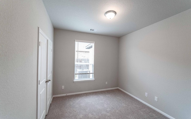 unfurnished room with carpet flooring and a textured ceiling