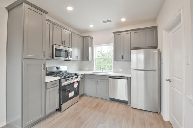 kitchen featuring gray cabinetry, stainless steel appliances, and light hardwood / wood-style floors