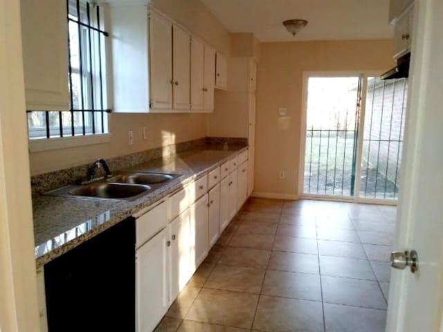 kitchen featuring stone countertops, white cabinetry, sink, and light tile patterned floors