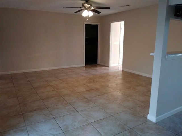 empty room with ceiling fan and light tile patterned floors