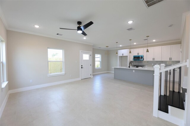 kitchen featuring decorative backsplash, an island with sink, white cabinets, decorative light fixtures, and ornamental molding