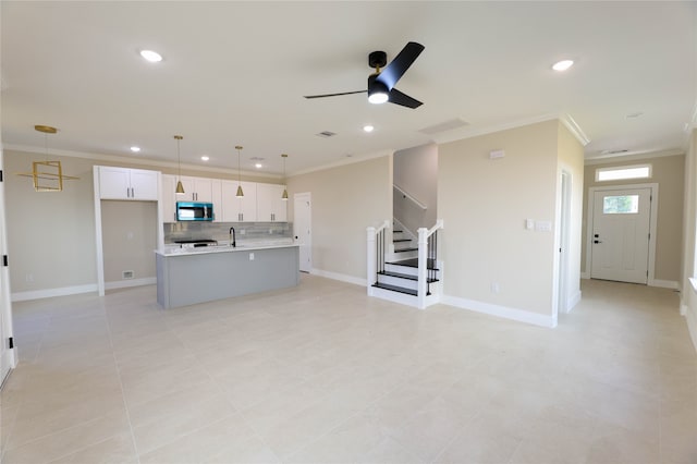 unfurnished living room with crown molding, light tile patterned flooring, sink, and ceiling fan