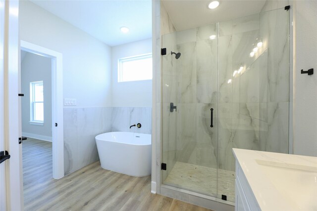 bathroom with tile walls, shower with separate bathtub, hardwood / wood-style floors, and vanity