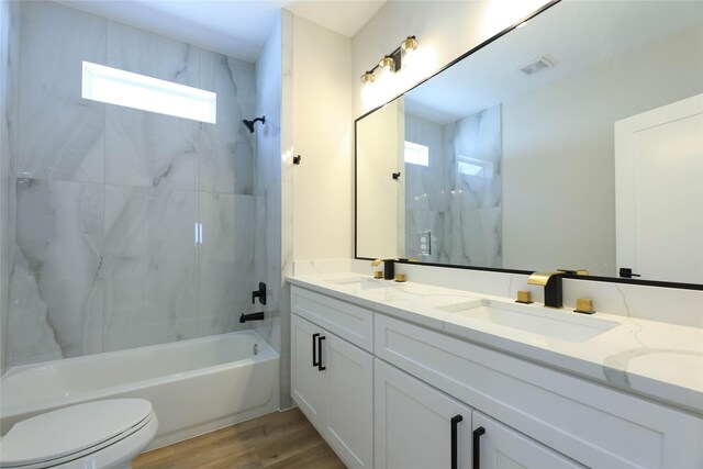 full bathroom featuring tiled shower / bath, hardwood / wood-style flooring, vanity, and toilet