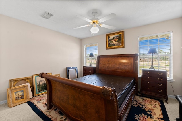 bedroom with baseboards, visible vents, a ceiling fan, and light colored carpet