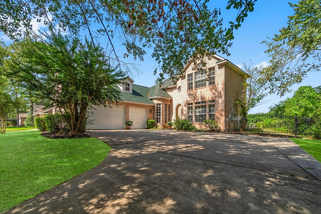 view of front of property featuring concrete driveway, an attached garage, fence, a front lawn, and brick siding