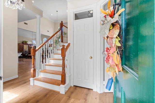 staircase with visible vents, crown molding, decorative columns, and wood finished floors