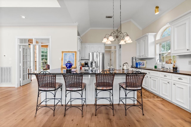 kitchen featuring pendant lighting, dark countertops, visible vents, and stainless steel fridge with ice dispenser