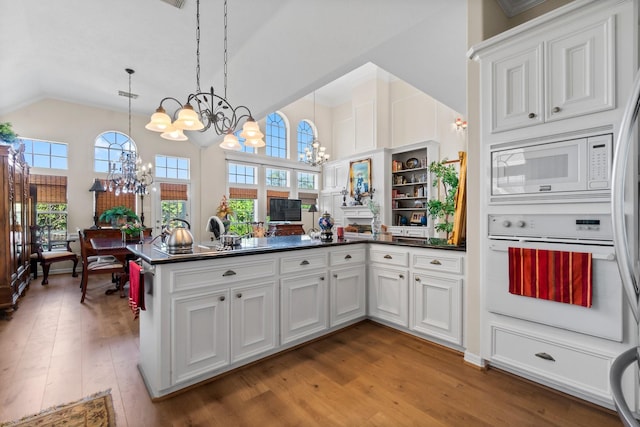 kitchen featuring a notable chandelier, white appliances, dark countertops, and white cabinets