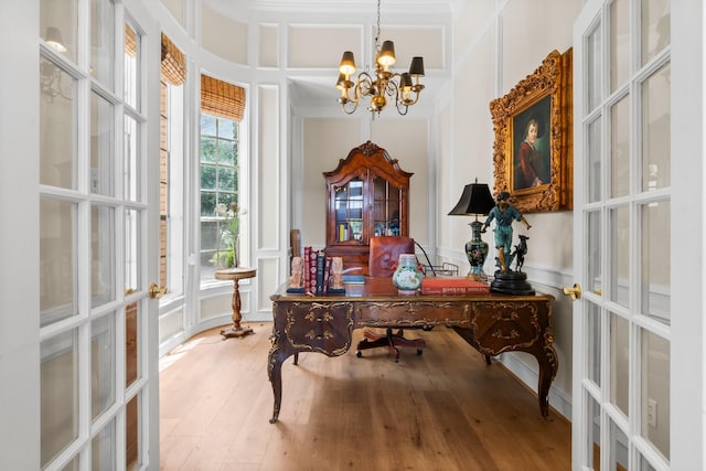 office space featuring a decorative wall, wood finished floors, french doors, an inviting chandelier, and crown molding