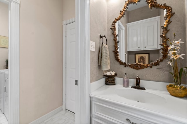 bathroom with marble finish floor, washer and clothes dryer, vanity, and baseboards