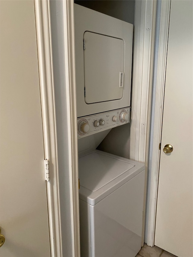 laundry room with stacked washer and dryer and light tile patterned floors