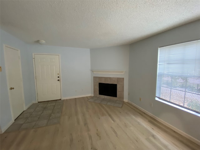 unfurnished living room featuring a fireplace, a textured ceiling, and light wood-type flooring