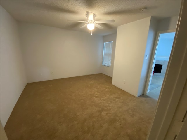 carpeted empty room with ceiling fan and a textured ceiling