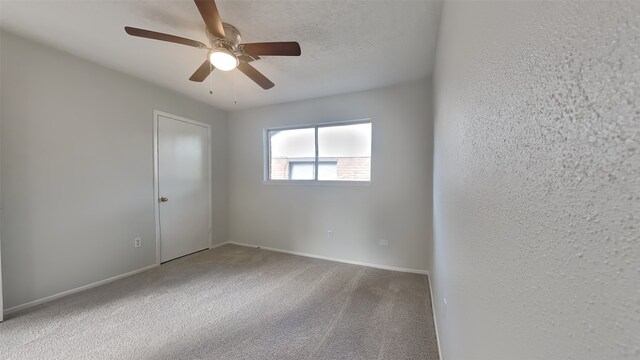 empty room featuring ceiling fan and carpet