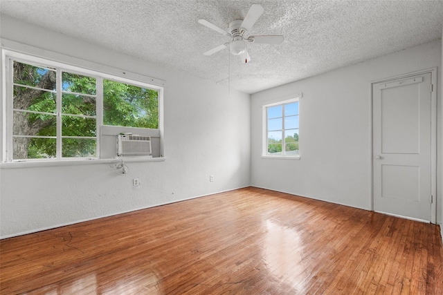 unfurnished room featuring hardwood / wood-style floors, cooling unit, ceiling fan, and a textured ceiling