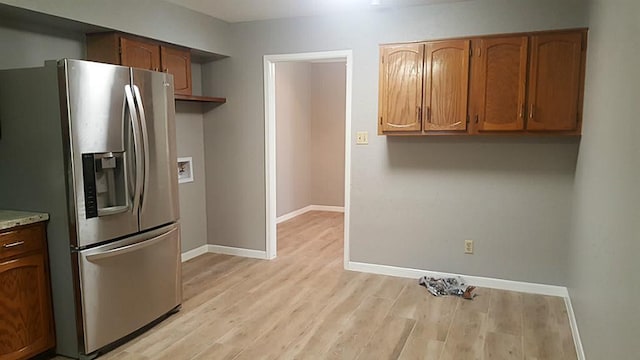 kitchen with light wood-type flooring, stainless steel refrigerator with ice dispenser, baseboards, and brown cabinets