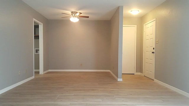 spare room featuring light wood-type flooring, a ceiling fan, and baseboards