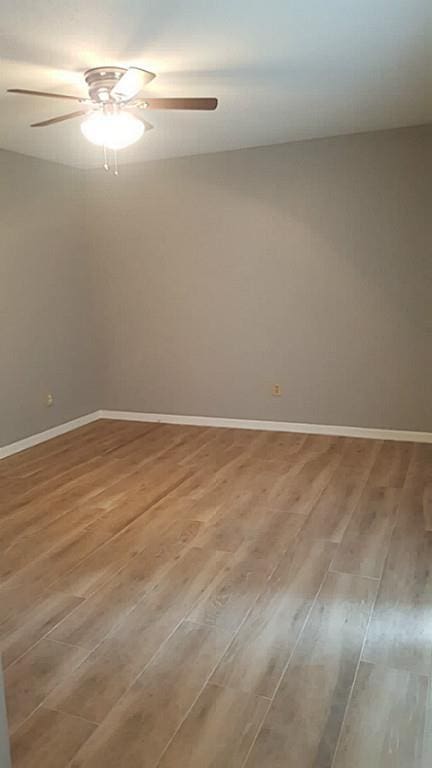 spare room featuring light wood-style flooring, baseboards, and ceiling fan