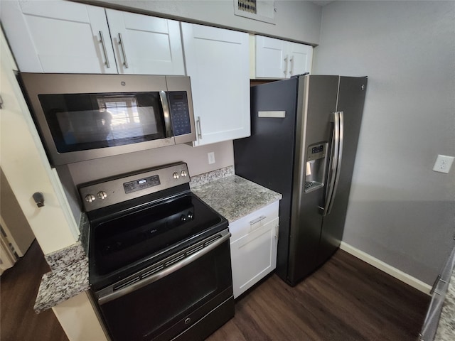 kitchen with stainless steel appliances, light stone counters, dark hardwood / wood-style flooring, and white cabinets