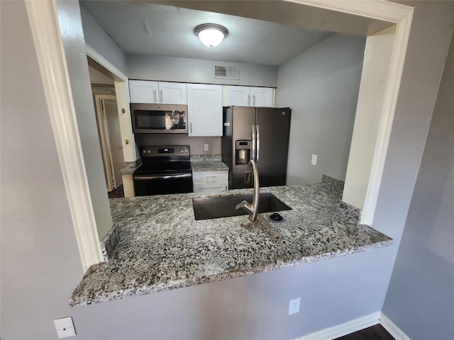 kitchen featuring a peninsula, light stone countertops, stainless steel appliances, and a sink