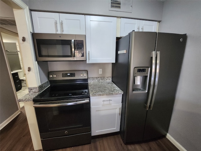 kitchen with appliances with stainless steel finishes, light stone counters, white cabinets, and dark hardwood / wood-style floors