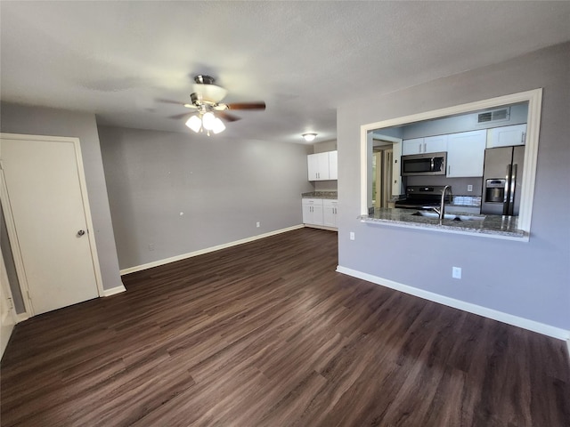unfurnished living room with dark wood-style floors, visible vents, a sink, baseboards, and ceiling fan