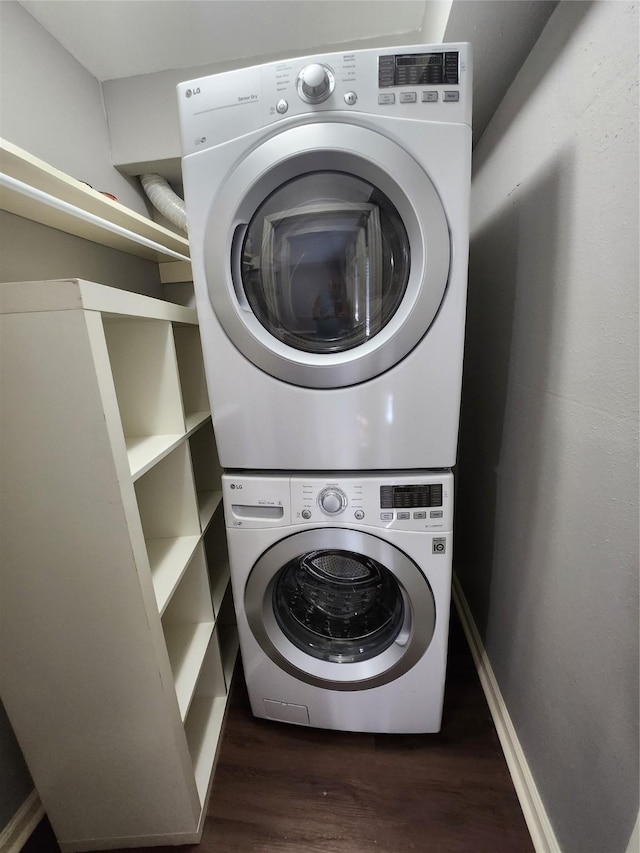 laundry room with stacked washer and dryer, baseboards, dark wood-style flooring, and laundry area