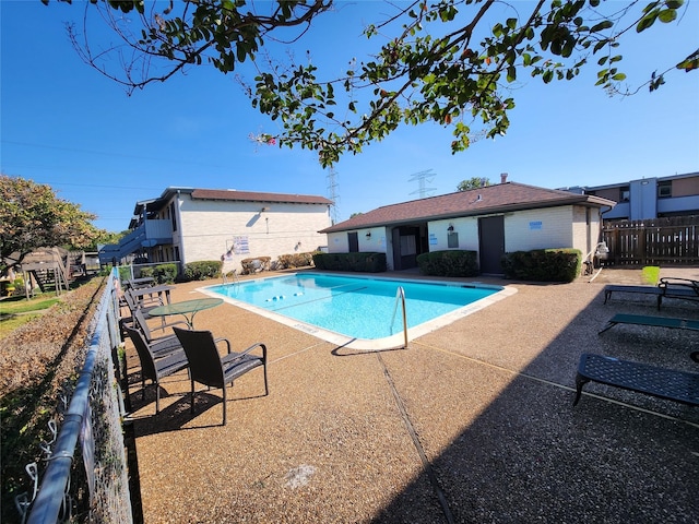 community pool with fence and a patio area