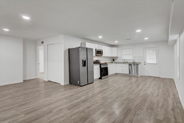 kitchen with sink, white cabinetry, stainless steel appliances, and light hardwood / wood-style flooring