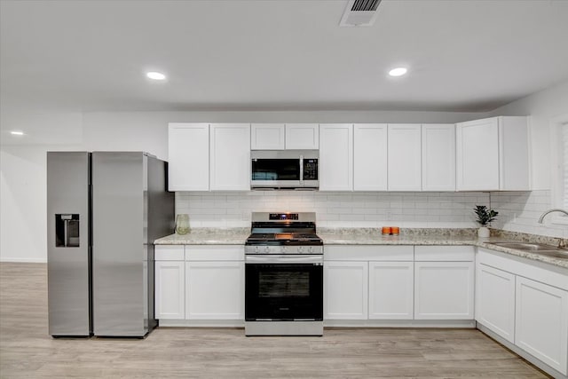 kitchen with white cabinets, appliances with stainless steel finishes, light hardwood / wood-style floors, and sink