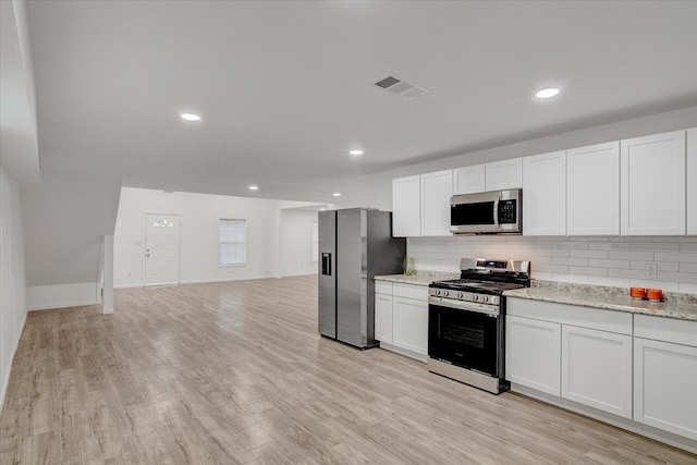 kitchen with white cabinets, appliances with stainless steel finishes, decorative backsplash, and light hardwood / wood-style flooring