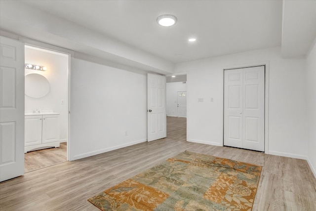 unfurnished bedroom featuring connected bathroom, light hardwood / wood-style flooring, and a closet