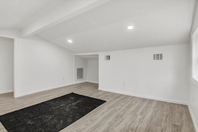 spare room featuring vaulted ceiling with beams and light hardwood / wood-style flooring