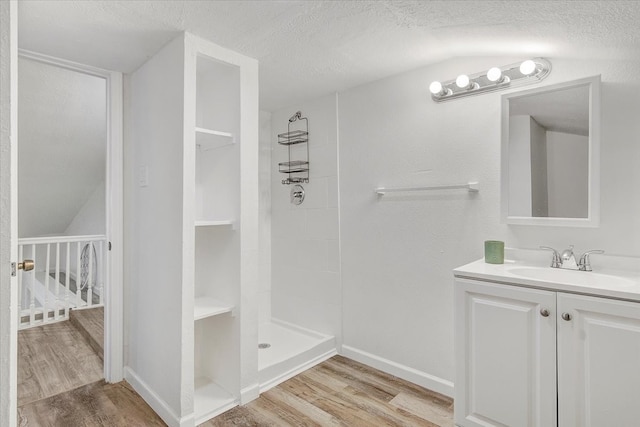 bathroom with vaulted ceiling, wood-type flooring, a textured ceiling, and tiled shower