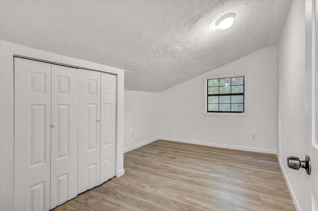 bonus room with a textured ceiling, light hardwood / wood-style flooring, and lofted ceiling