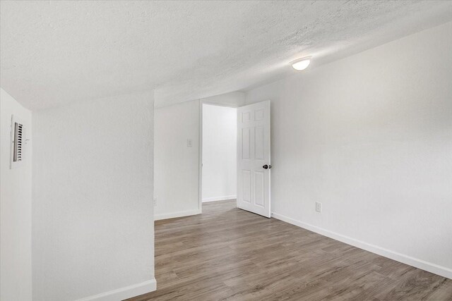 empty room with wood-type flooring and a textured ceiling