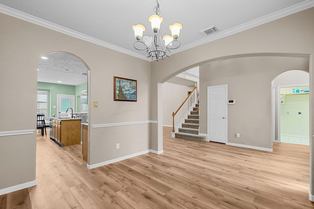 interior space with a sink, visible vents, baseboards, light wood-style floors, and ornamental molding