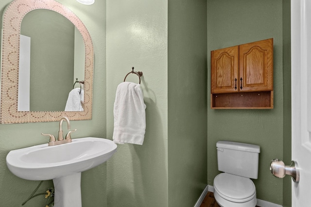 half bath with a sink, toilet, and baseboards