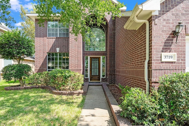 entrance to property with a yard and brick siding