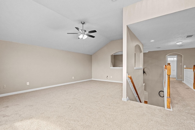 interior space featuring arched walkways, carpet floors, visible vents, baseboards, and vaulted ceiling