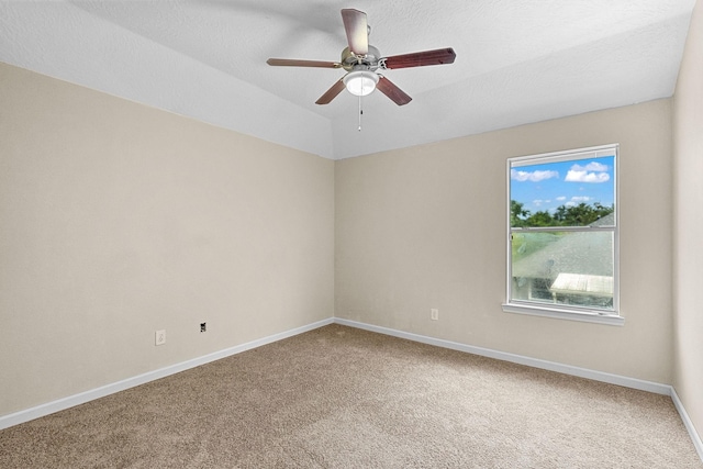 carpeted empty room featuring lofted ceiling, a textured ceiling, baseboards, and a ceiling fan