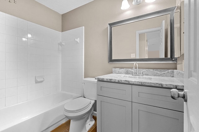 bathroom with a textured ceiling, toilet, wood finished floors, vanity, and tub / shower combination