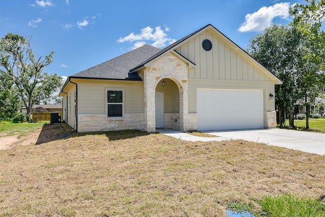 view of front of property with a garage, central air condition unit, and a front lawn