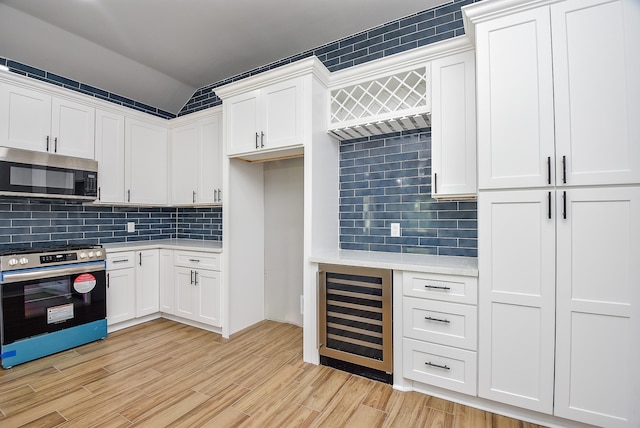 kitchen with appliances with stainless steel finishes, light hardwood / wood-style flooring, decorative backsplash, wine cooler, and white cabinets