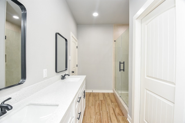 bathroom with an enclosed shower, hardwood / wood-style floors, and double sink vanity