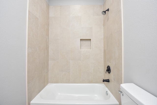 bathroom featuring tiled shower / bath combo and toilet