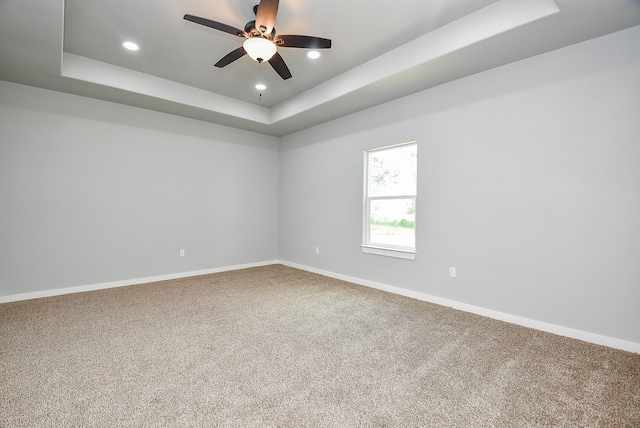 unfurnished room with carpet, a raised ceiling, and ceiling fan