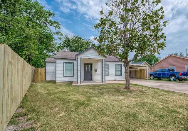 view of front of property with a front lawn, fence, driveway, and a shingled roof